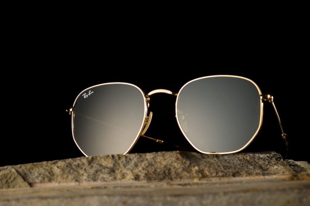 Close-up of gold-rimmed sunglasses on a stone surface against a black background.